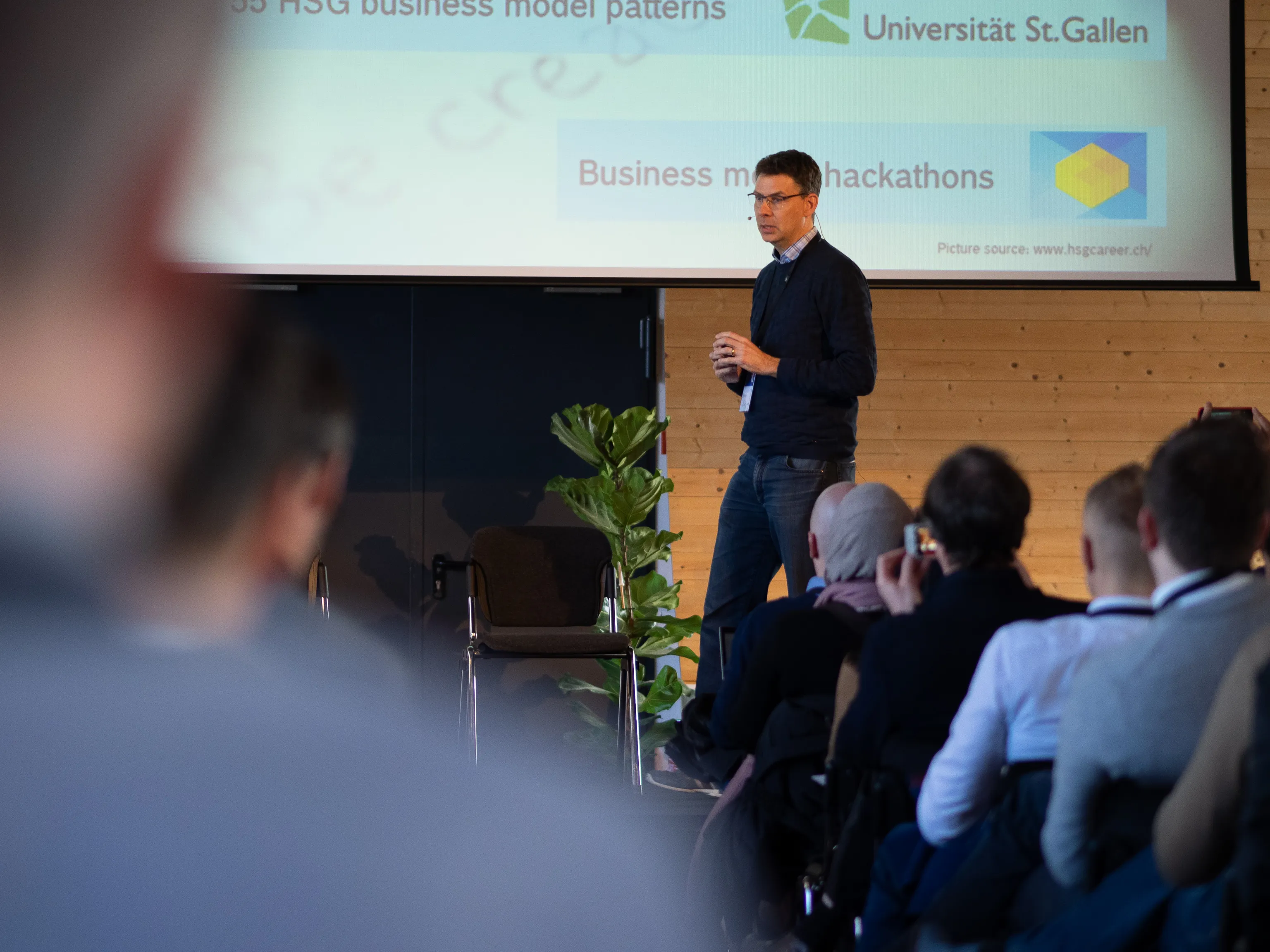 A speaker presents business model patterns to a seated audience.