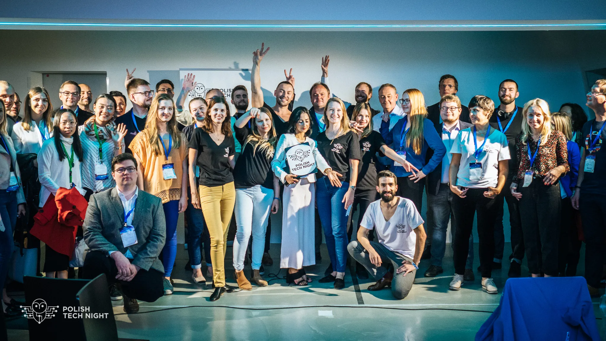 A large group poses onstage with a Polish Tech Night sign.