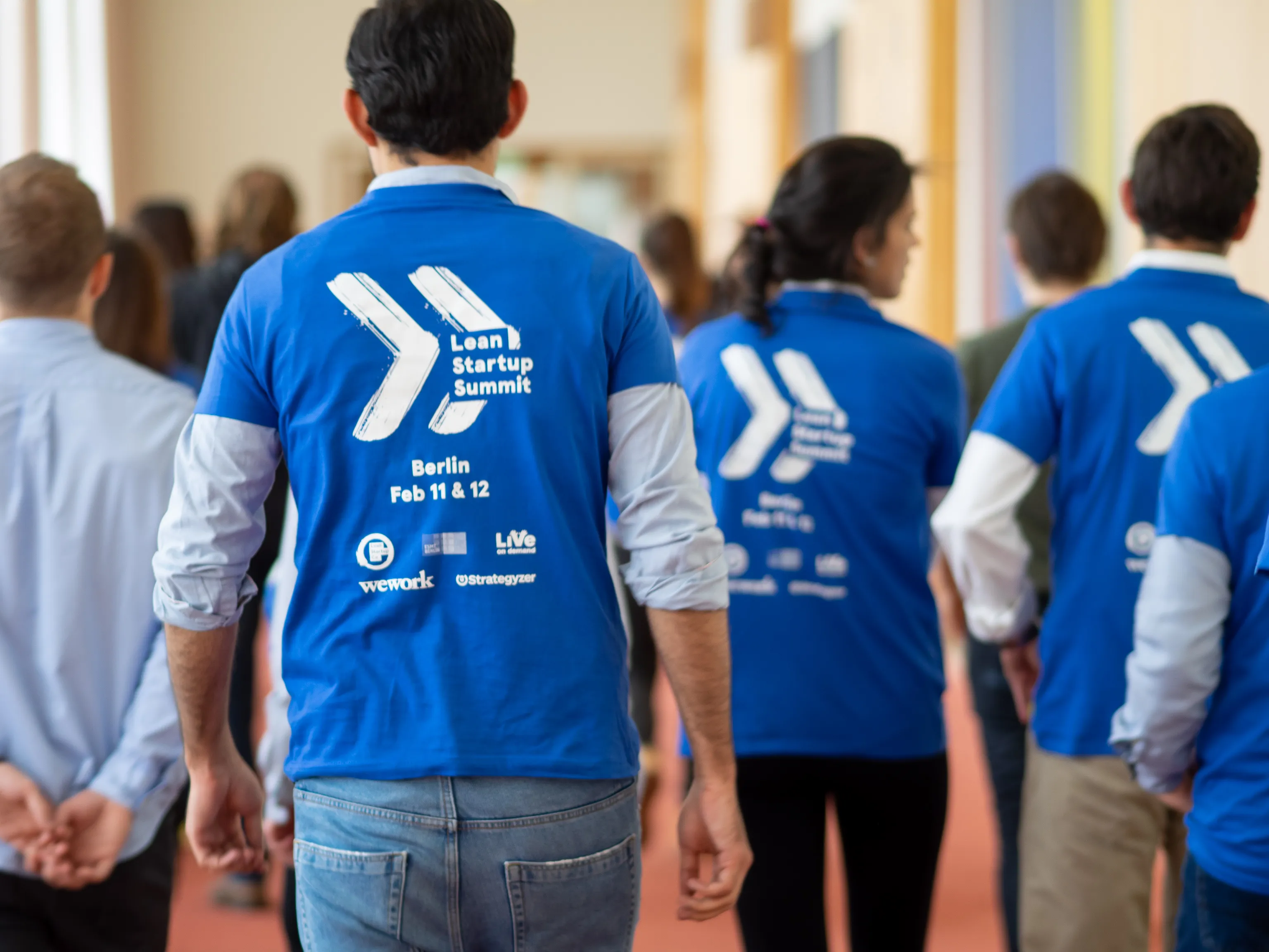 Staff in blue Lean Startup Summit shirts walk through the venue.