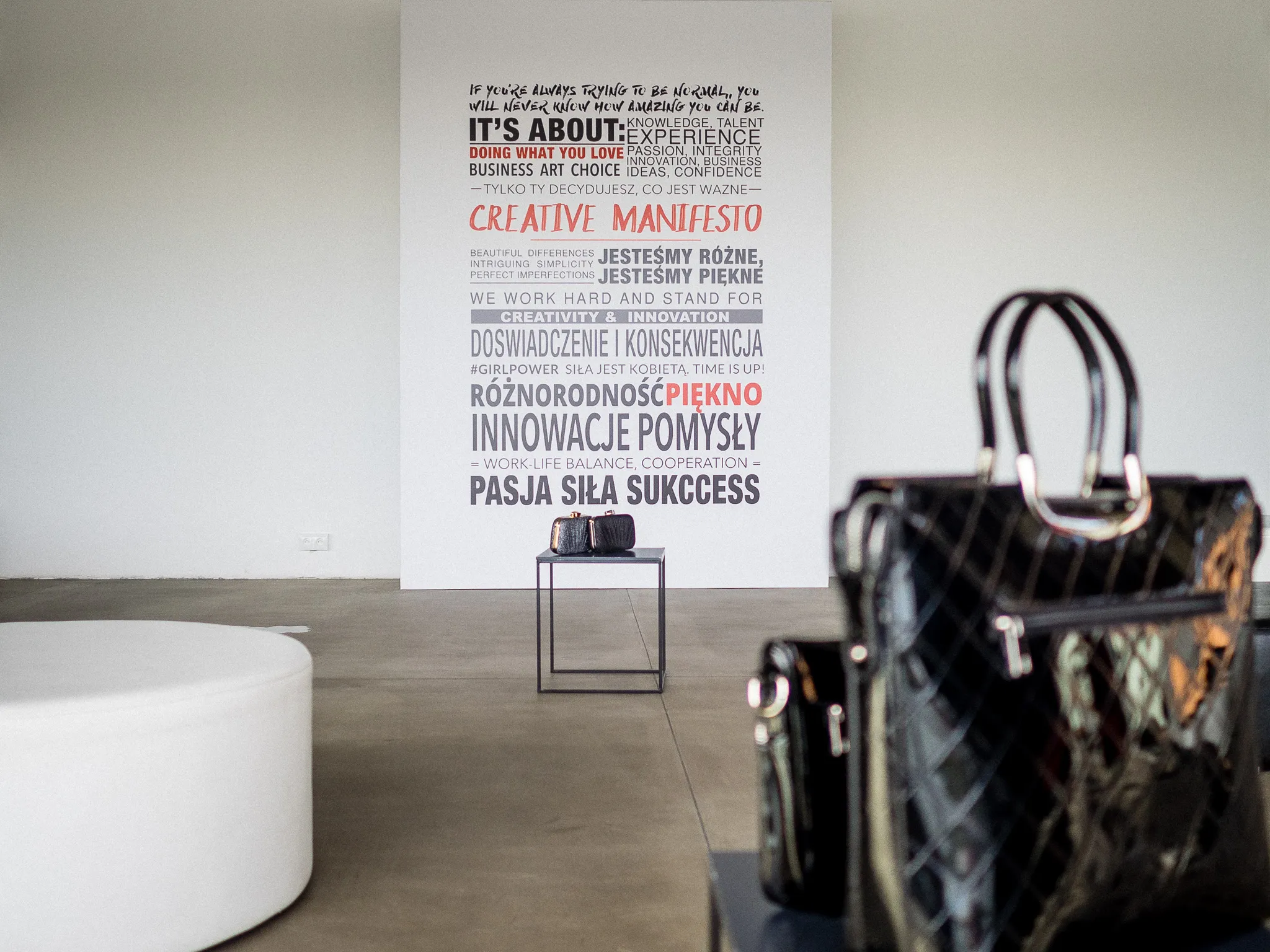Minimal Quiosque showroom with a Creative Manifesto wall graphic and handbags on display.