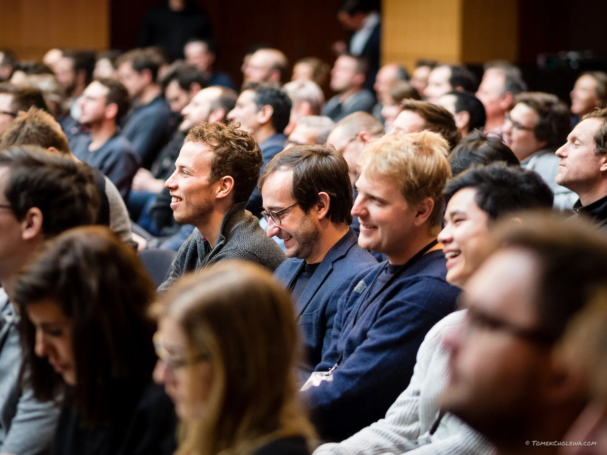 Smiling audience members react during a session in the packed auditorium.